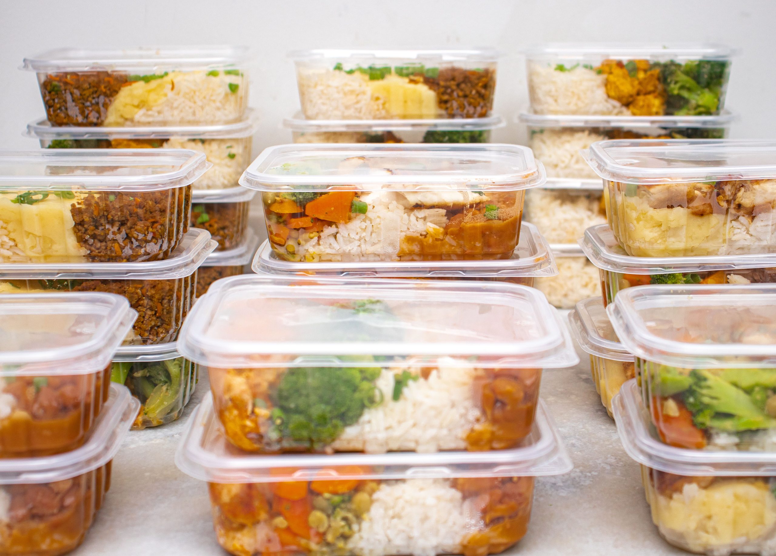 Prepared meal containers with rice and vegetables lined up for the week