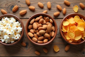 Assortment of low-sodium snacks and chips including nuts, popcorn, and rice cakes in bowls on a table